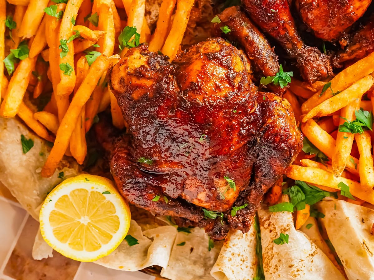 Pollo entero a la brasa sobre tabla, con papas fritas al costado